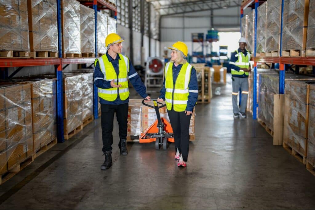 Warehouse team discussing inventory management while working efficiently in a safe environment.