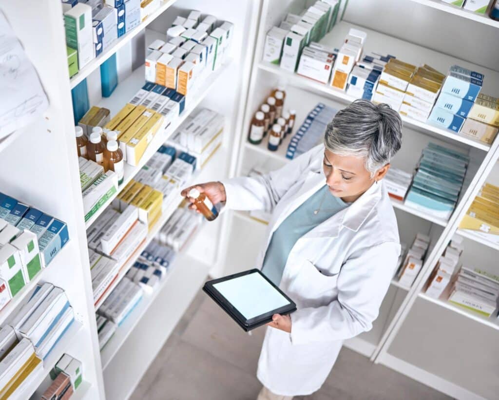 Pharmacist using a tablet to manage medications in a pharmacy.