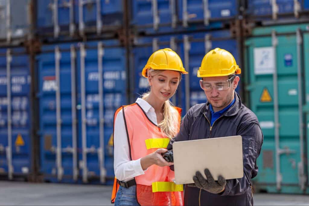 Workers collaborating on data analysis in a shipping yard.
