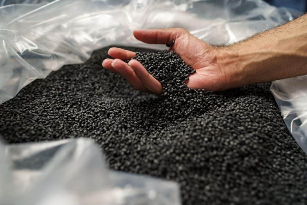 Hand interacting with black granules, showcasing unique textures and materials.