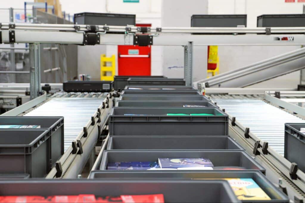 Automated warehouse conveyor system transporting bins for efficient inventory management.