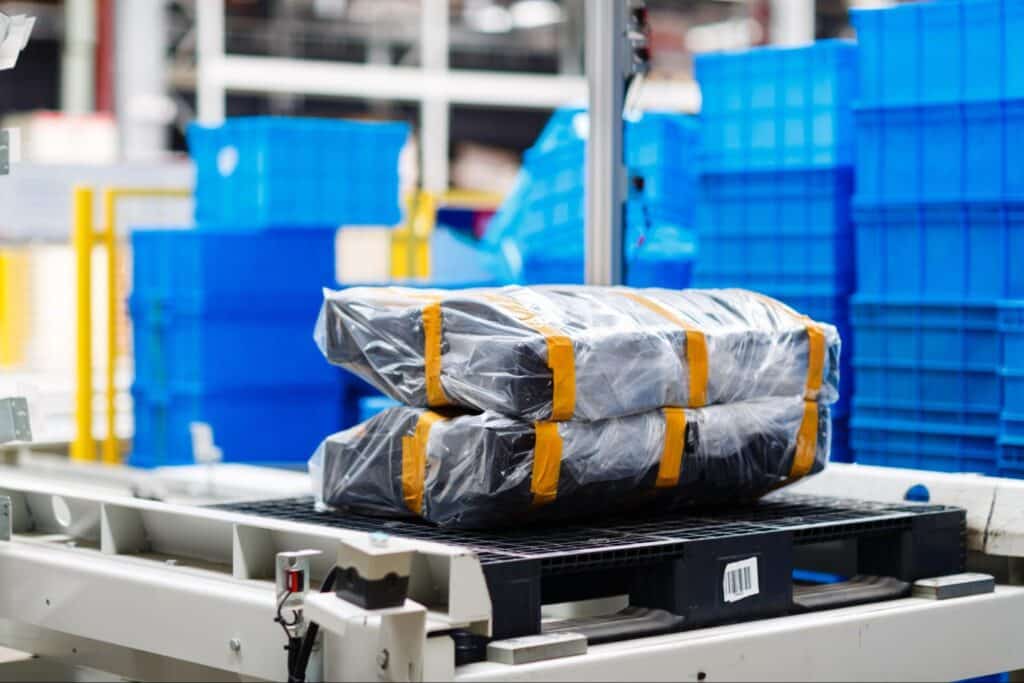 Packages ready for shipment in a modern warehouse with blue storage bins.