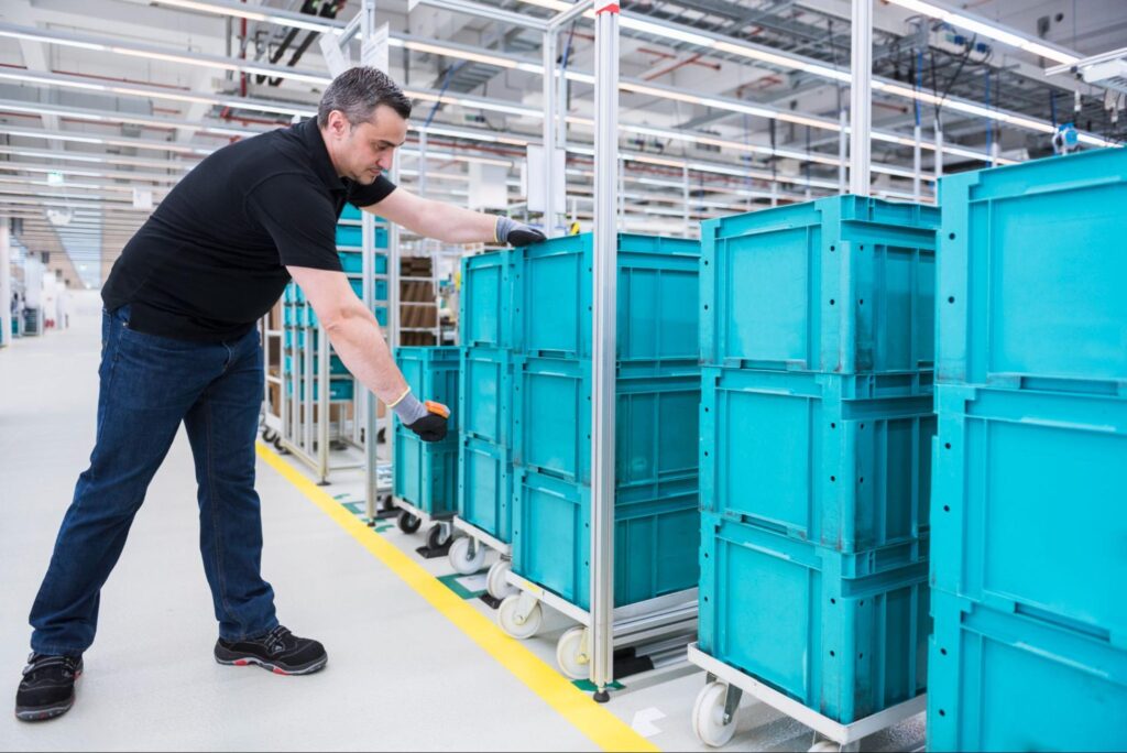 A worker organizes storage bins in a modern warehouse for efficient inventory management.