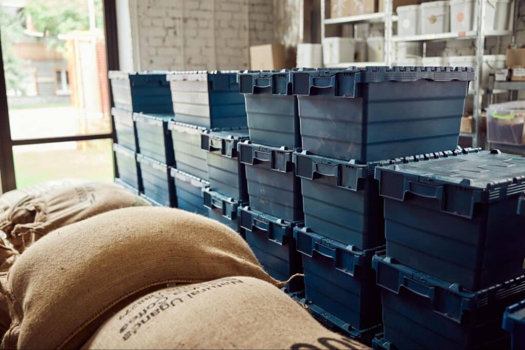 Stacked blue storage bins and burlap sacks in a warehouse setting.