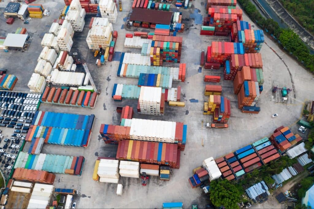 Aerial view of colorful shipping containers arranged at a busy logistics yard.