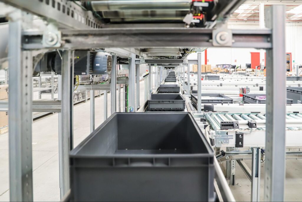 Automated conveyor system with empty bins in a warehouse setting.