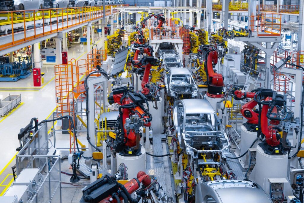 Automotive manufacturing facility with robotic arms assembling vehicles on production line.