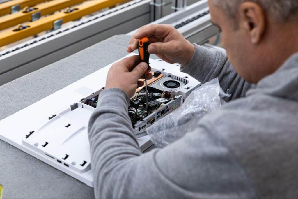 Technician repairing electronic equipment with tools on a workbench.
