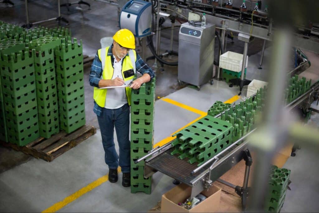 Worker inspecting green packaging for quality assurance in a manufacturing facility.